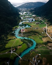 An aerial view of a clean river winding through a vibrant green valley, illustrating the beauty of unspoiled nature.