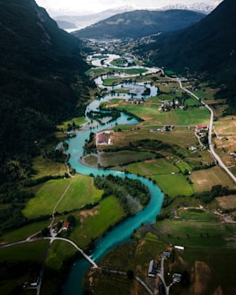 An aerial view of a clean river winding through a vibrant green valley, illustrating the beauty of unspoiled nature.