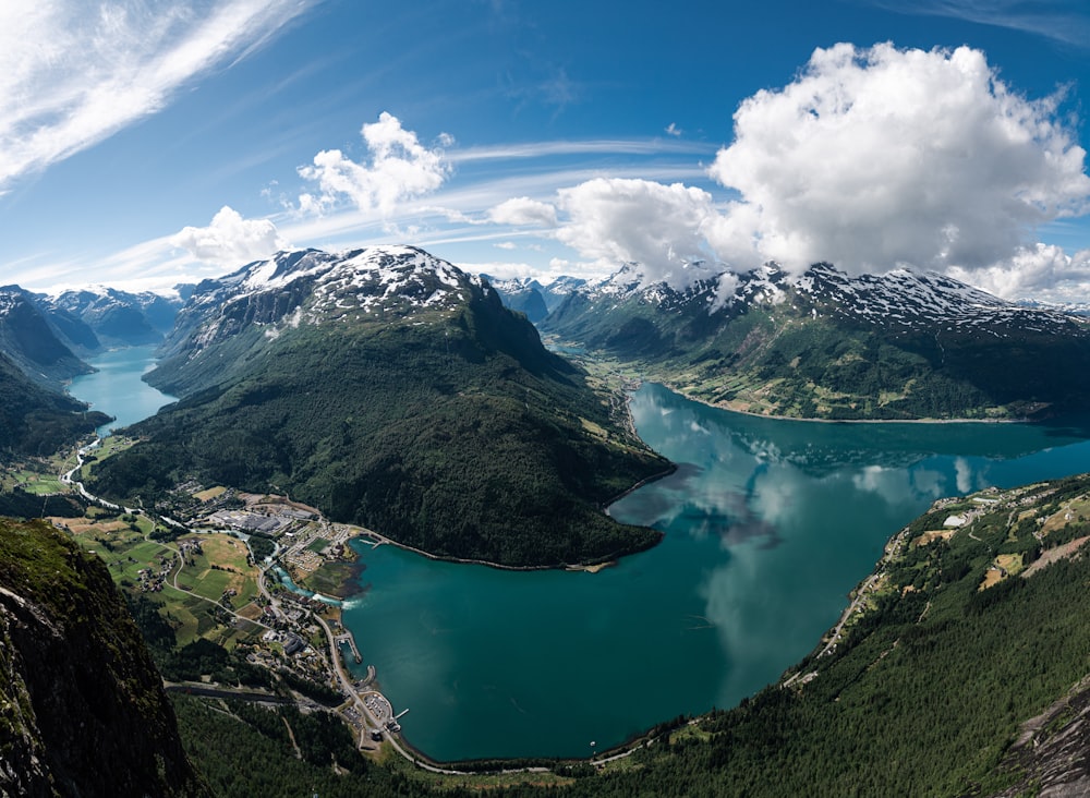 green lake surrounded by mountains under blue sky during daytime