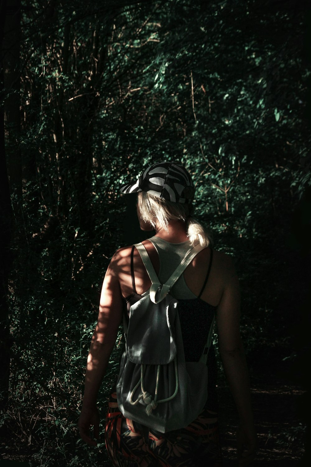 Frau in schwarzem Spaghettiträgerkleid tagsüber im Wald stehend