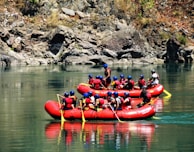 people riding on red kayak on river during daytime