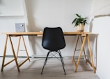 Minimalist wooden office desk with chair and indoor plant decoration.