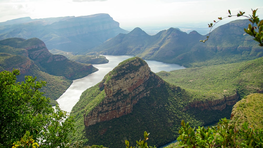 green and brown mountain beside body of water during daytime