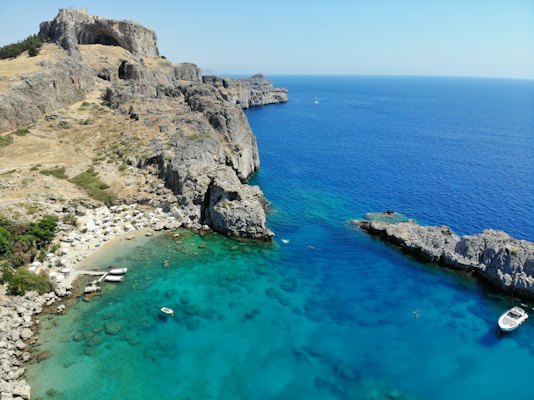 Brown rocky mountain beside blue sea under blue sky during daytime — Rhodes, Greece