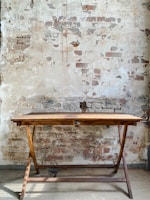 brown wooden folding table beside white concrete wall