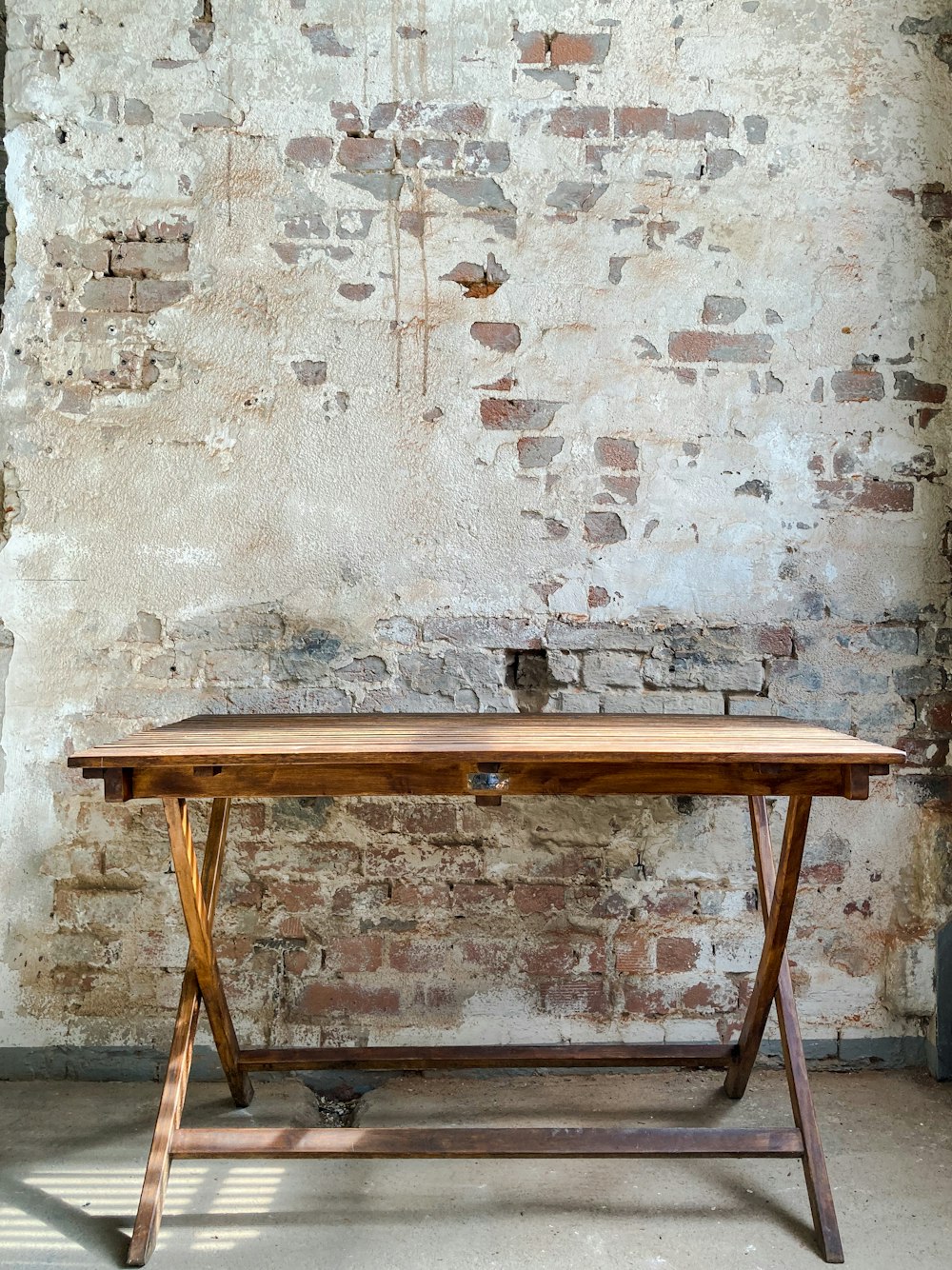 brown wooden folding table beside white concrete wall