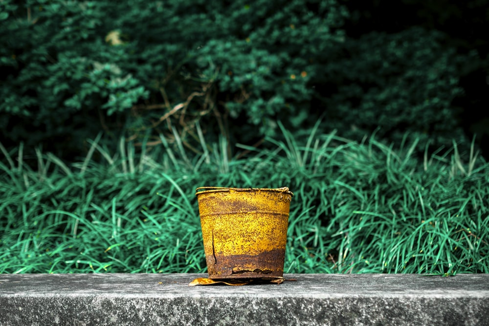 yellow and red steel bucket on gray concrete surface