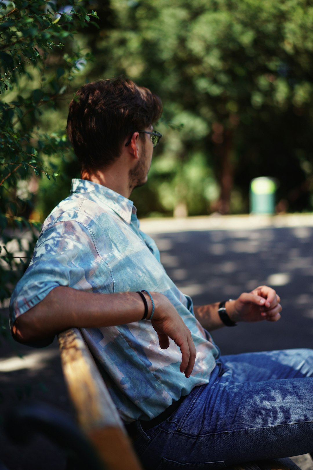 man in blue and white button up shirt sitting on brown wooden bench during daytime