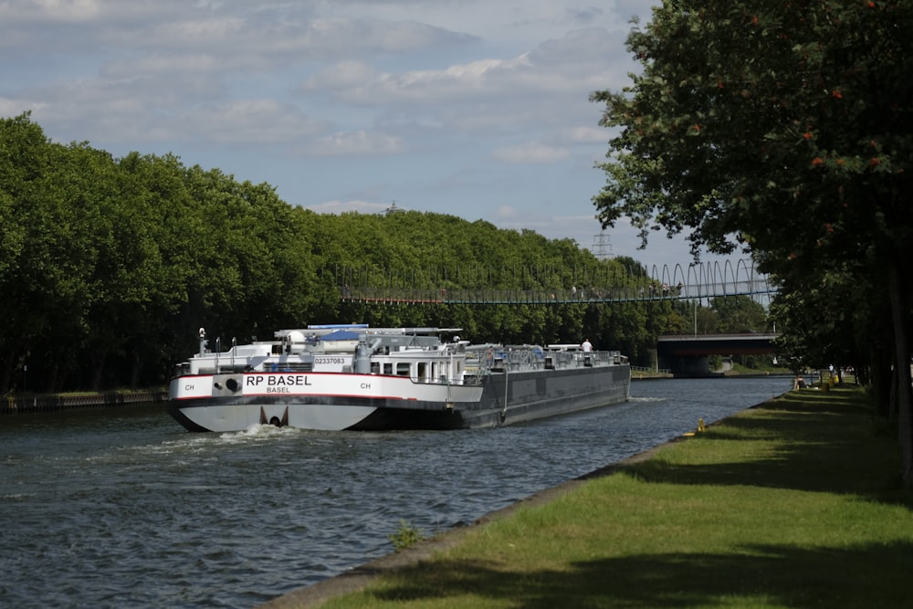 white yacht on body of water near green trees during daytime