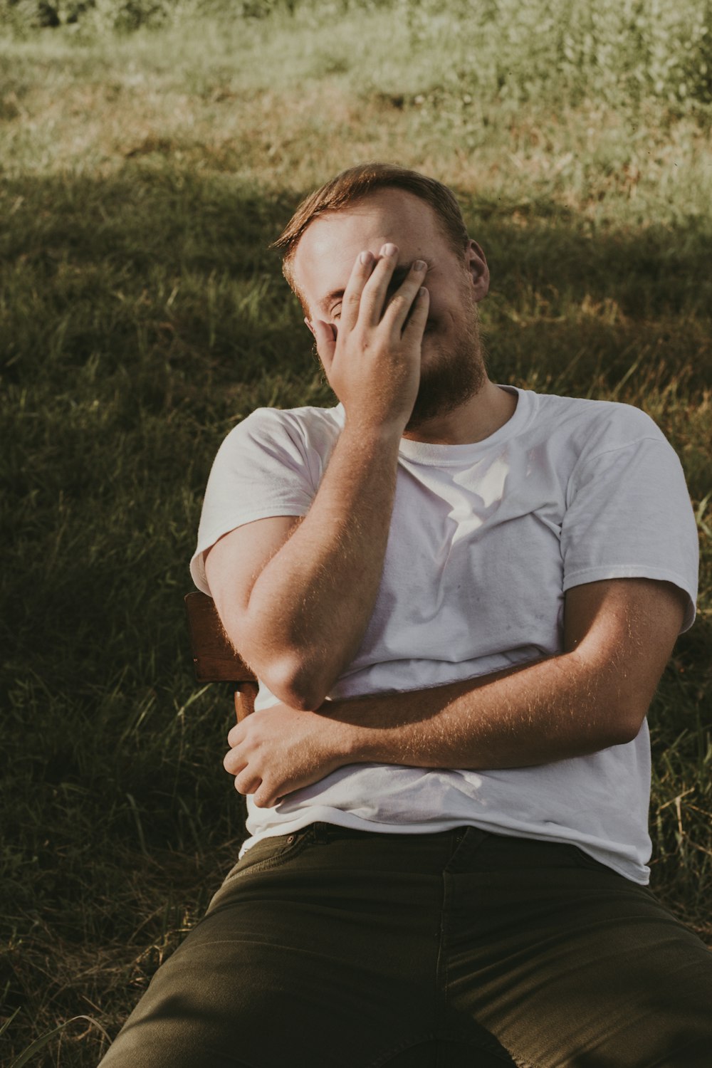 man in white crew neck t-shirt covering his face with his hand