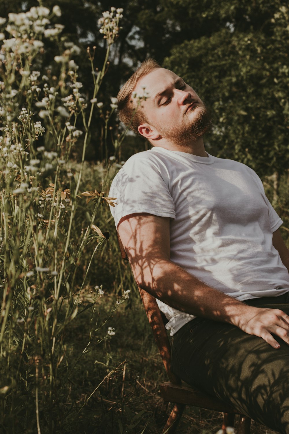 man in white crew neck t-shirt sitting on brown wooden seat