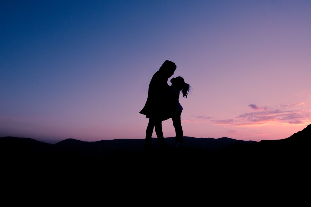 silhouette of man and woman kissing during sunset