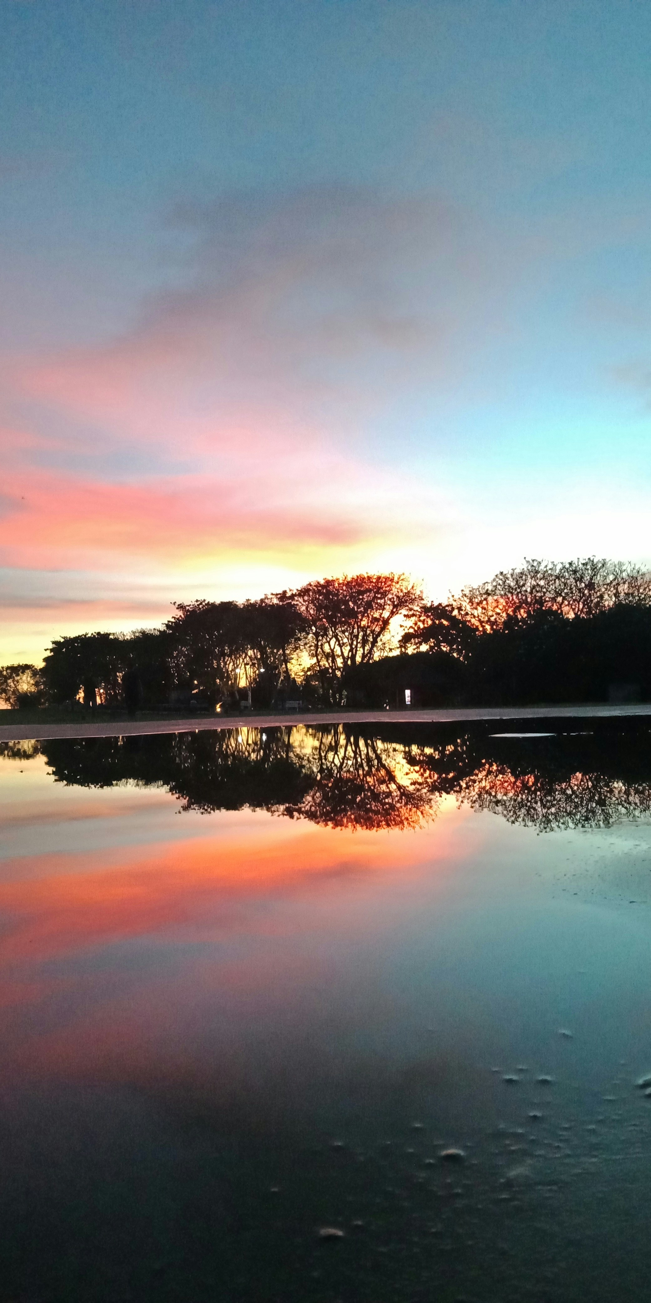 Sunset over Maldives lagoon with pink and orange sky reflecting on calm water
