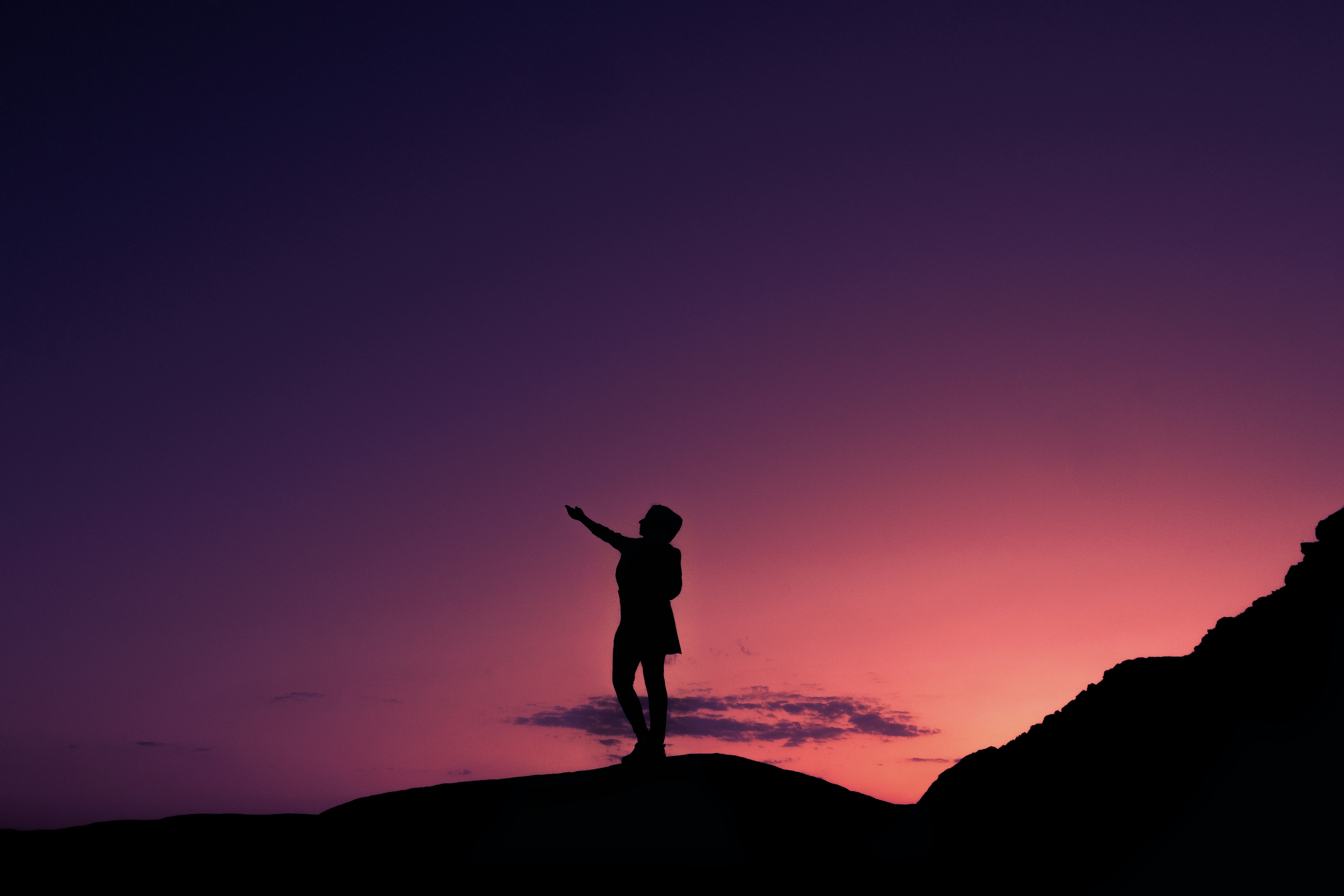 silhouette of man standing on rock during sunset