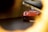 A red sports car partially visible through a blurred circular opening, possibly taken from a unique angle, enhancing the depth and focus on the car's front grille and sleek design.