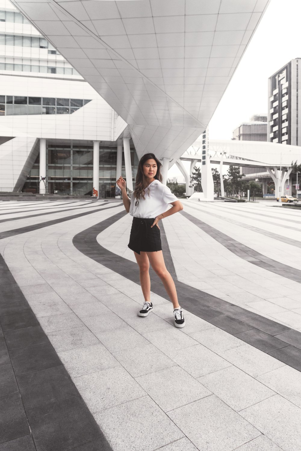 woman in white shirt and black skirt standing on pedestrian lane during daytime