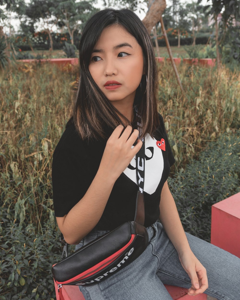 woman in black and white t-shirt and blue denim jeans sitting on red bench