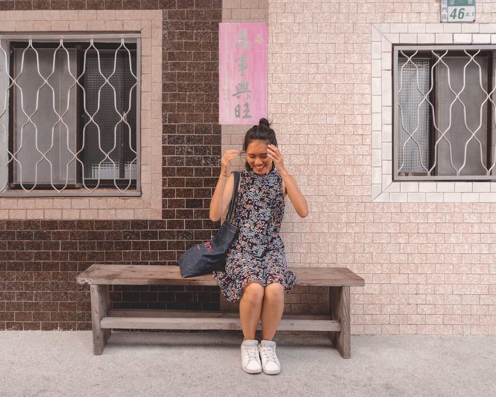 woman in blue and white floral dress sitting on brown wooden bench