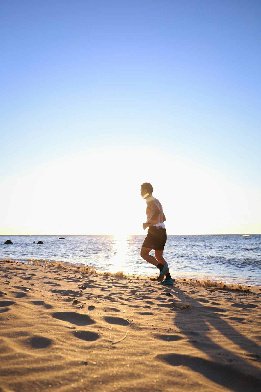 man in black shorts running on beach during daytime