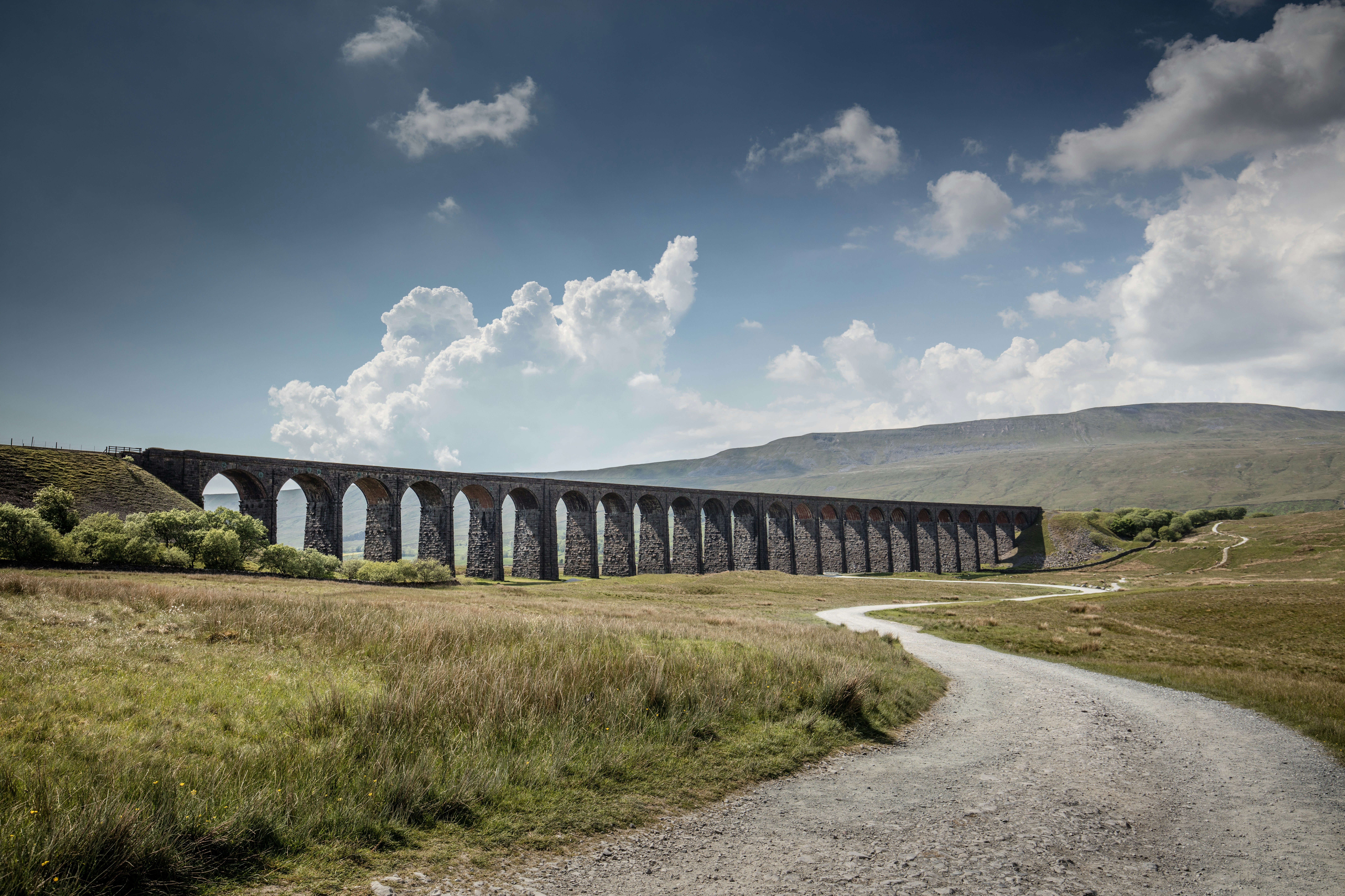 gray concrete bridge under blue sky and white clouds during daytime