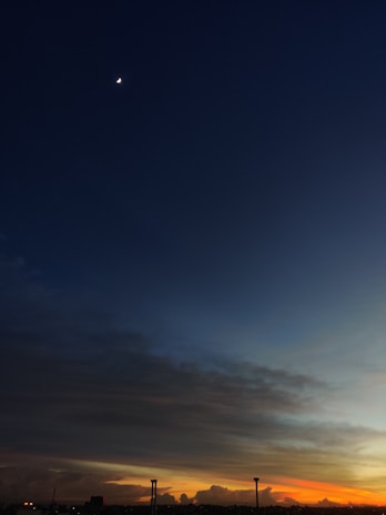 A poetic scene of a blue sky at dusk with Arabic calligraphy softly glowing, text aligned to the right.