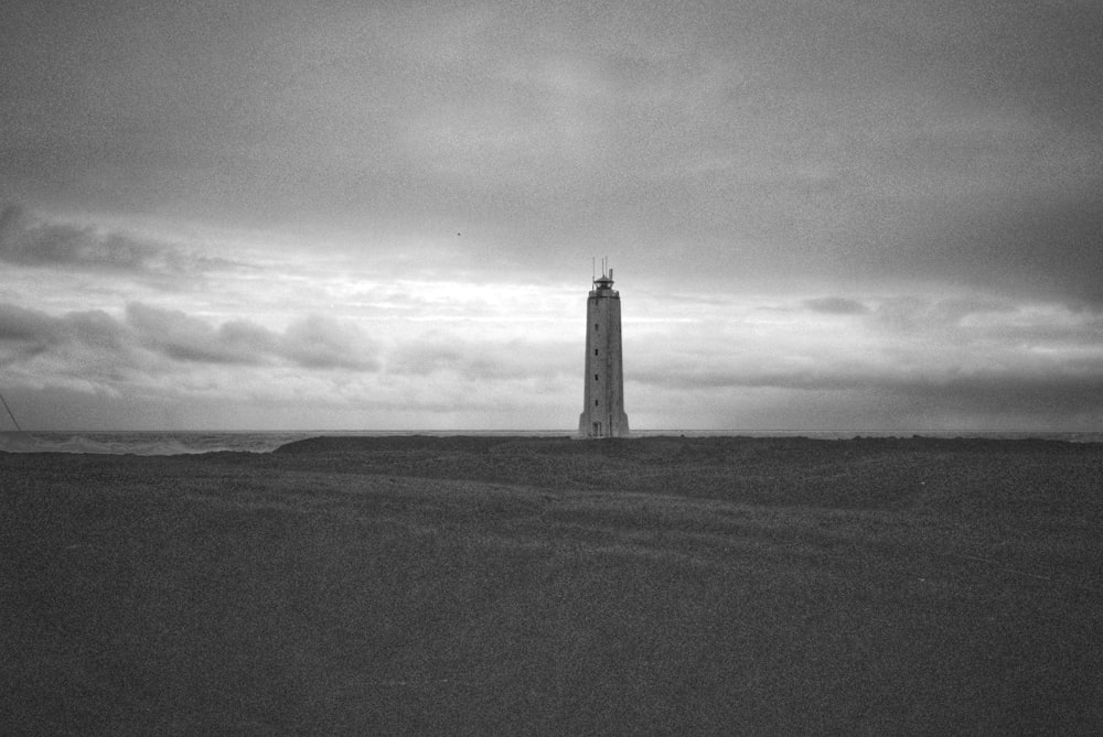 Graustufenfoto von Leuchtturm auf Hügel