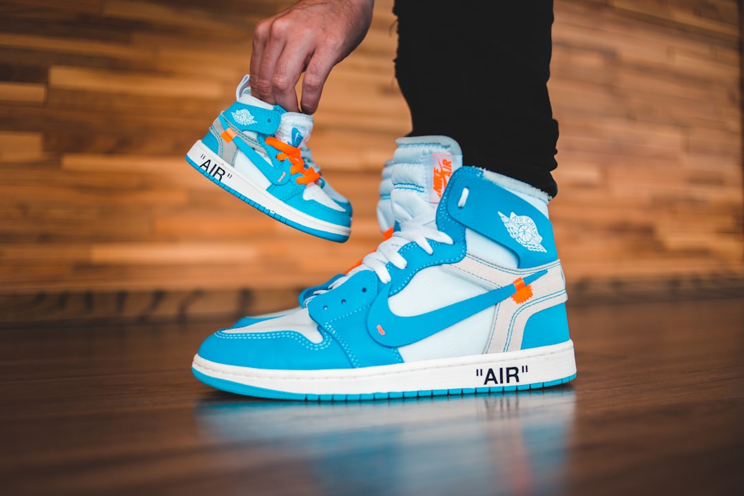 person wearing white blue and orange nike air jordan 1 shoes