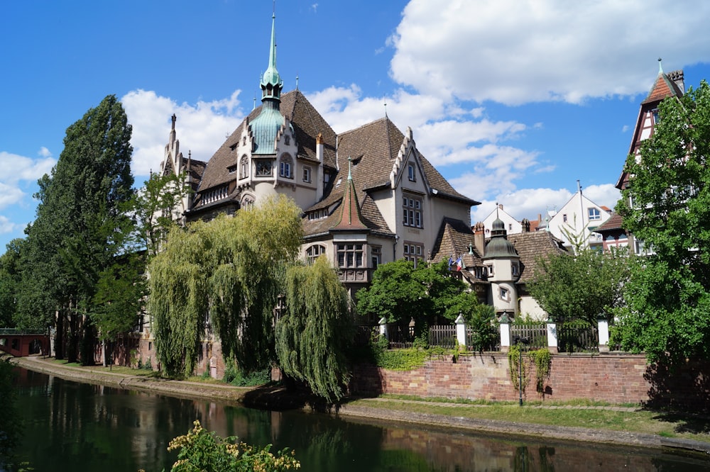 Edificio in cemento bianco e marrone vicino agli alberi verdi e al fiume sotto il cielo blu durante il giorno