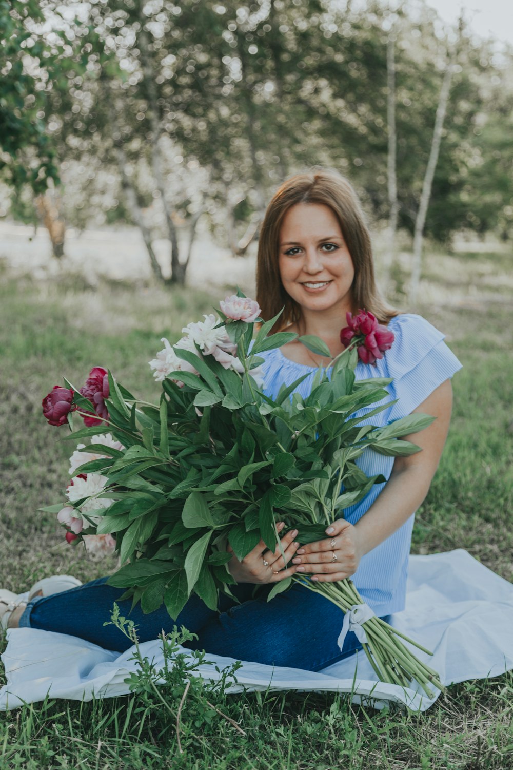 woman in white dress holding red flowers