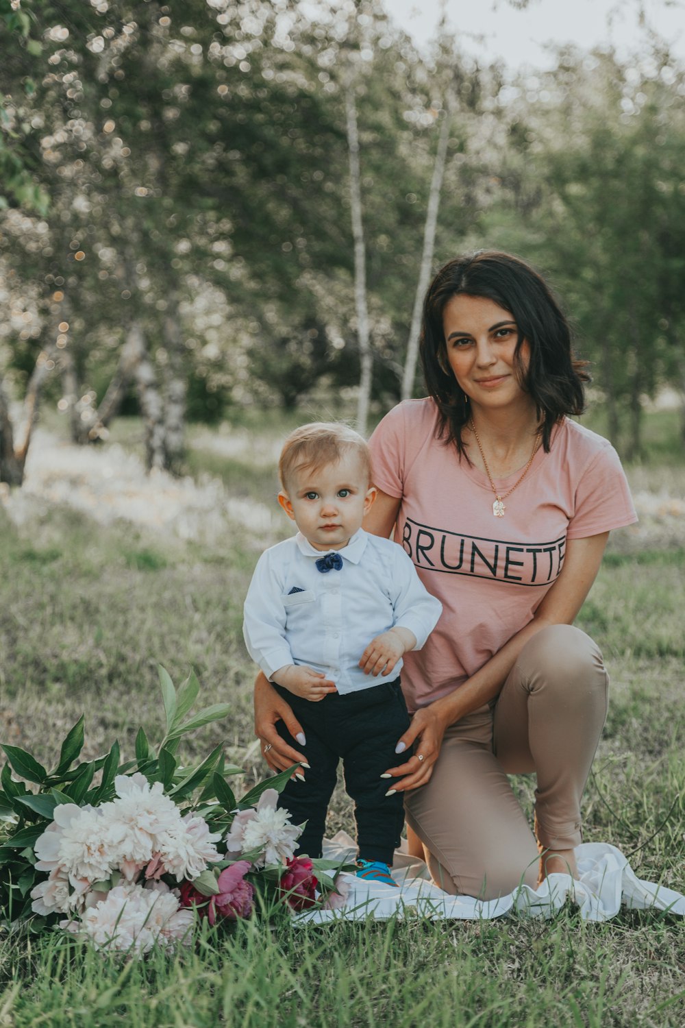 woman in pink shirt carrying baby in white onesie