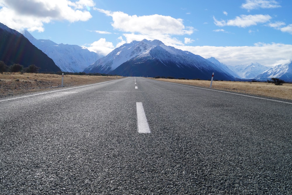 Carretera de asfalto gris cerca de la cordillera bajo el cielo azul durante el día