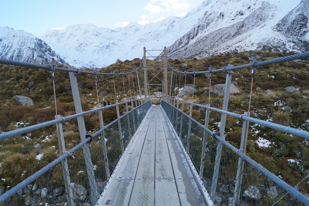 brown wooden bridge on snow covered mountain during daytime