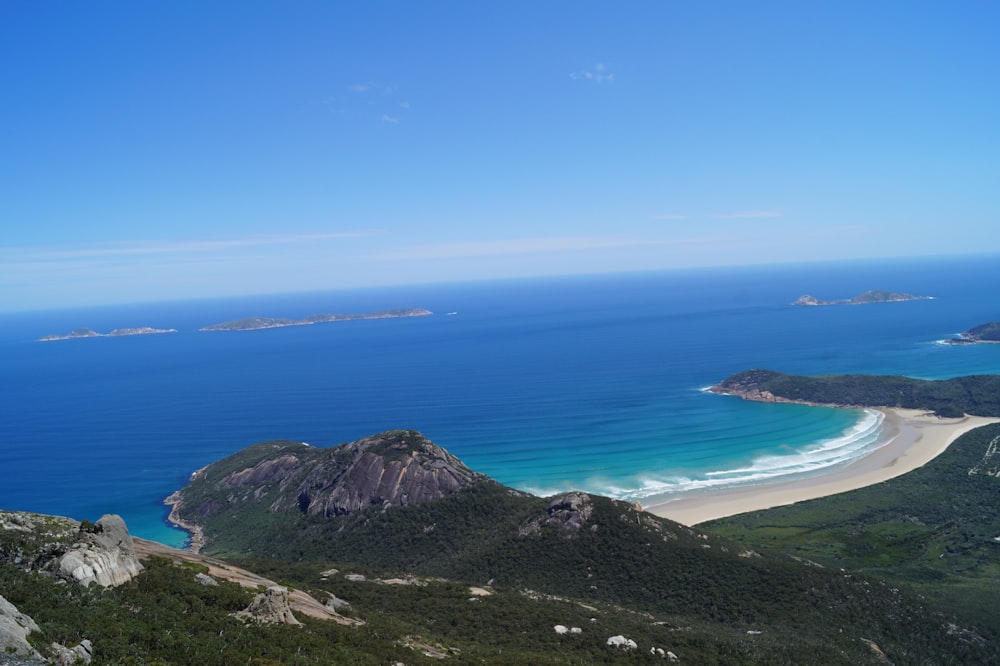 campo de hierba verde cerca del mar azul bajo el cielo azul durante el día