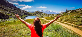 woman in red t-shirt standing on green grass field during daytime
