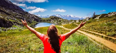 woman in red t-shirt standing on green grass field during daytime