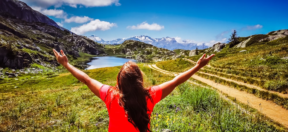 woman in red t-shirt standing on green grass field during daytime