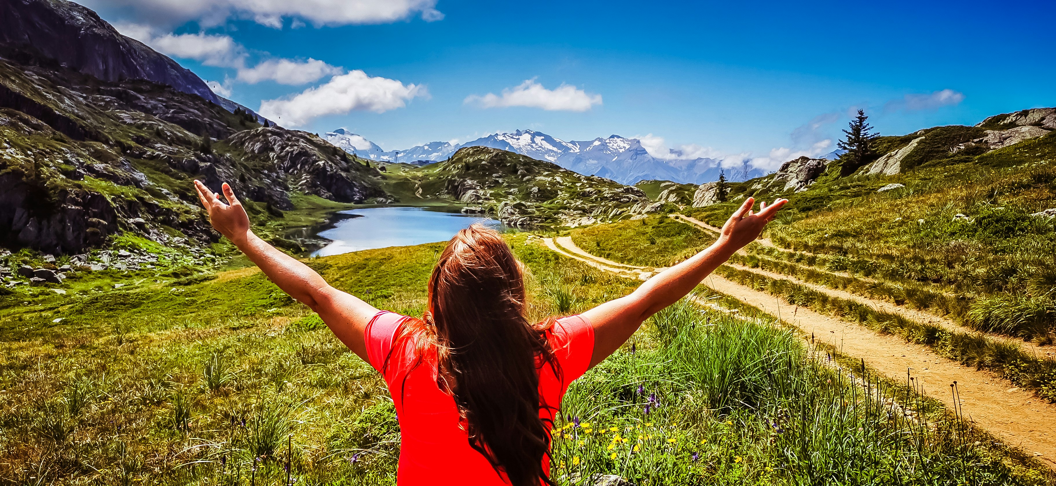 woman in red t-shirt standing on green grass field during daytime