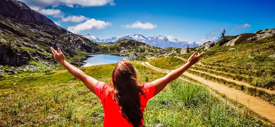 woman in red t-shirt standing on green grass field during daytime in Alpe d'Huez France