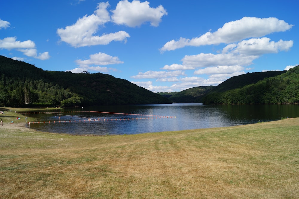 lake near green mountain under blue sky during daytime