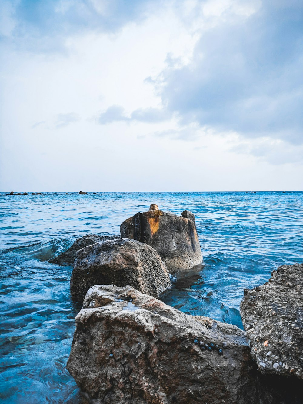 person standing on rock formation near sea during daytime