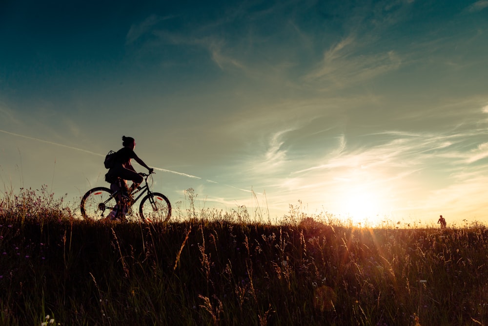 a person riding a bike in a field at sunset