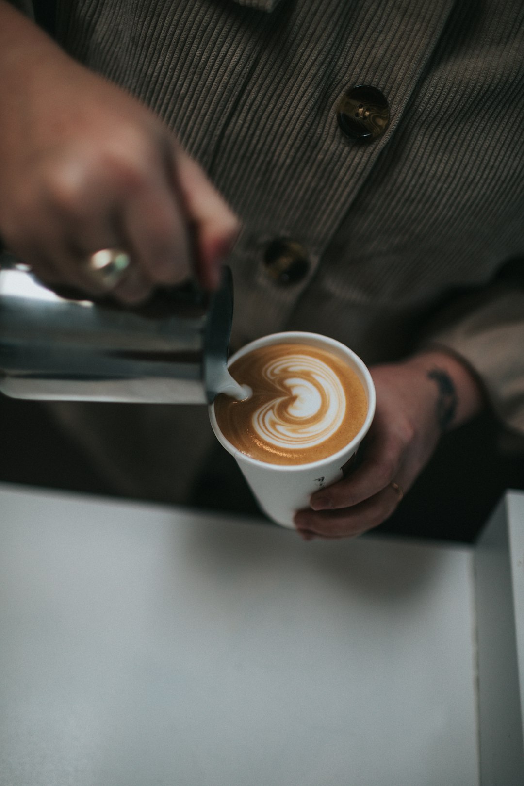 person holding white ceramic mug with cappuccino