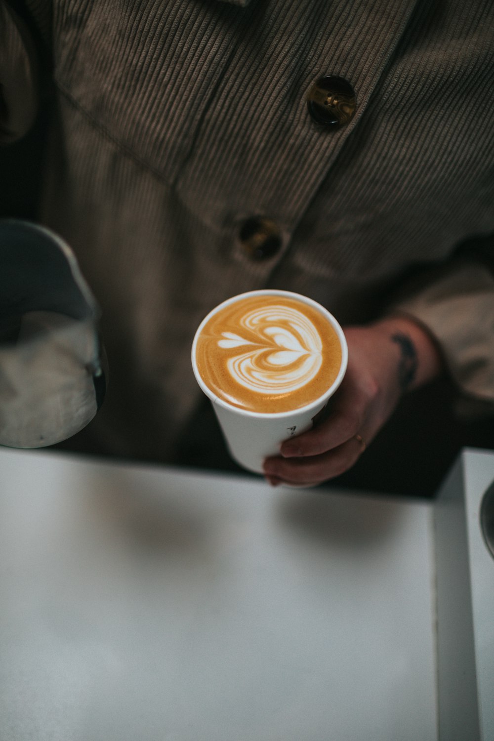 person holding white ceramic cup with brown liquid