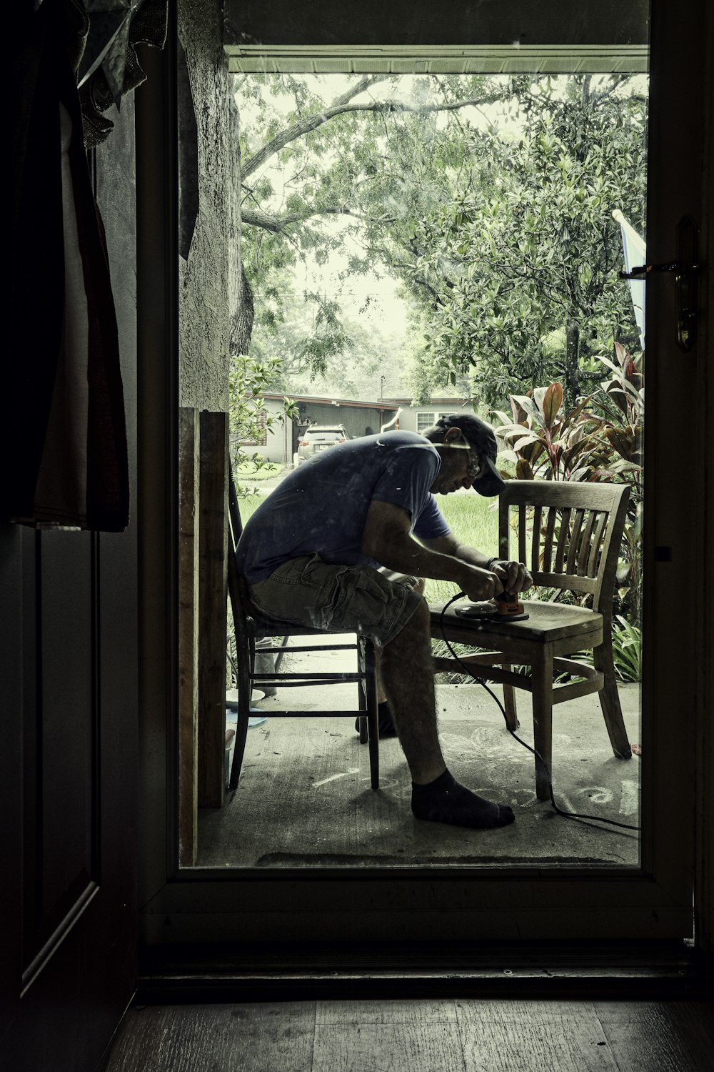 man in blue t-shirt sitting on brown wooden chair