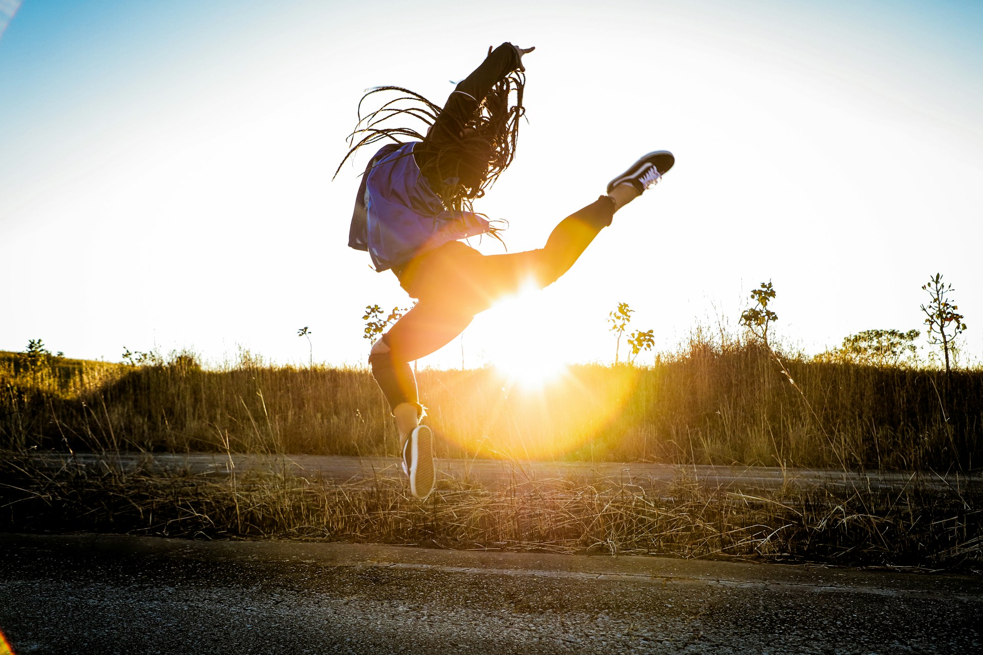 woman in black jacket and white shorts jumping on road during daytime