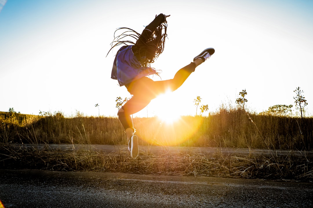 woman in black jacket and white shorts jumping on road during daytime