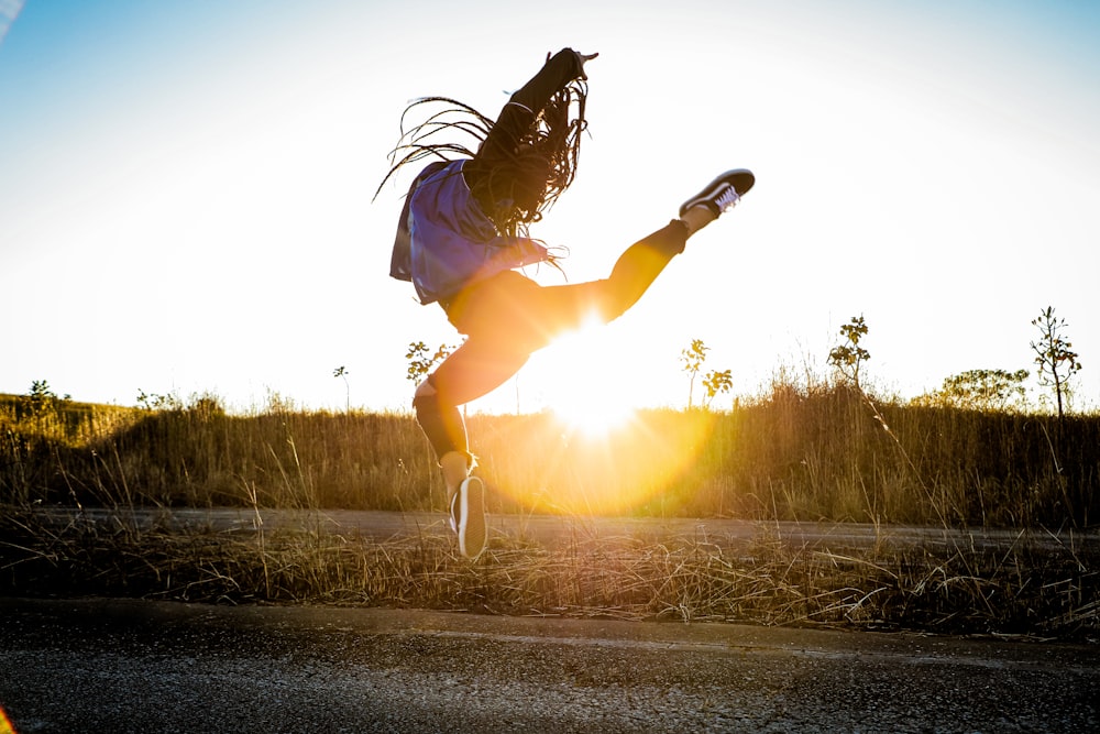 woman in black jacket and white shorts jumping on road during daytime