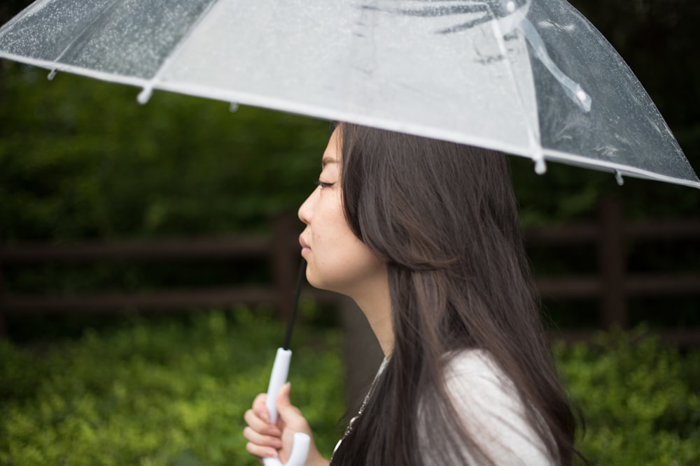 Frau, die tagsüber einen weißen Regenschirm hält