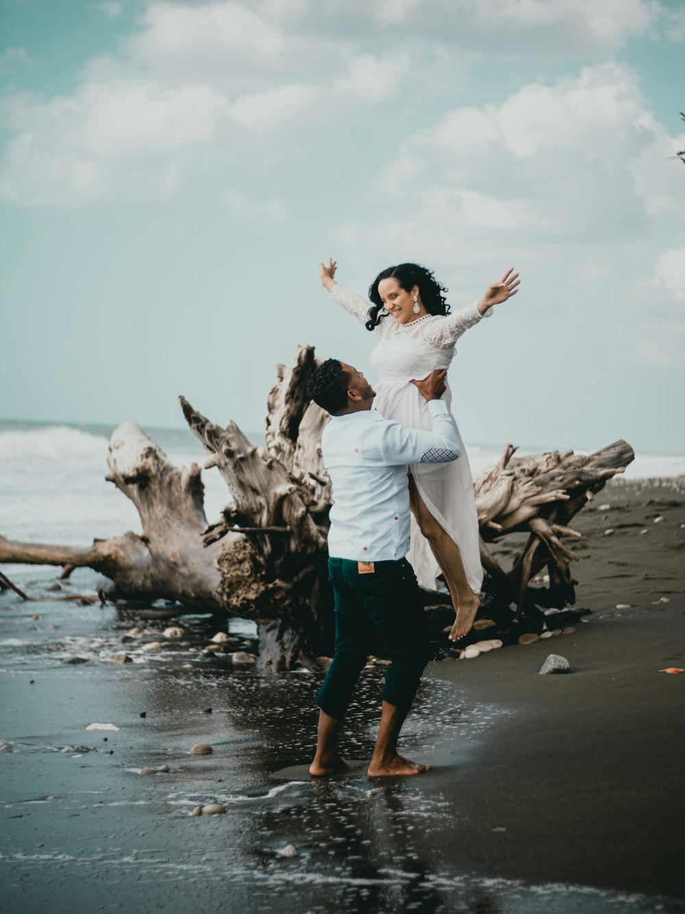 man and woman standing on beach shore during daytime