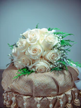 A lush bridal bouquet of deep emerald greens and soft cream roses accented with gold ribbons.